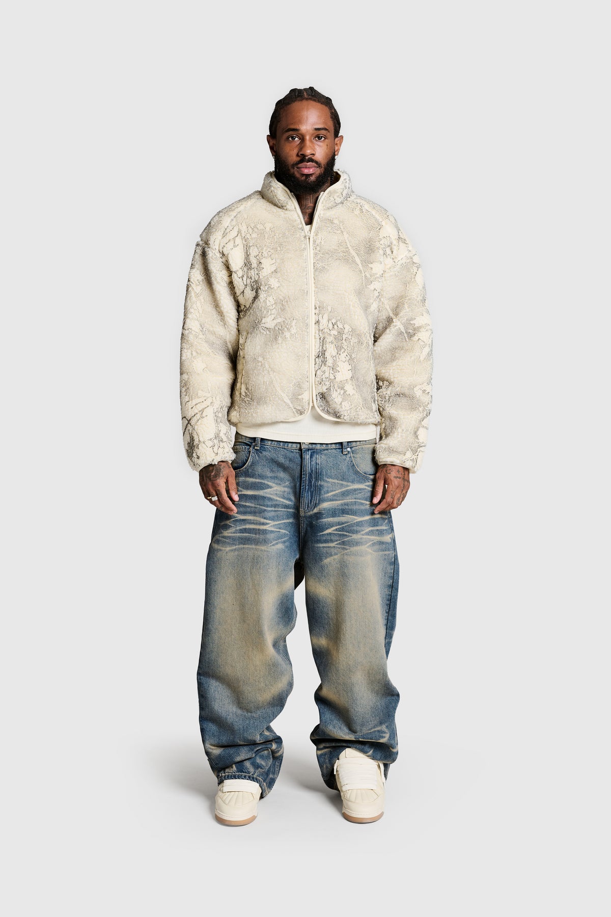 A man stands facing forward wearing the PESOCLO Hunter Fleece—a beige textured regular fit jacket—paired with loose blue jeans and white sneakers against a plain light gray background.