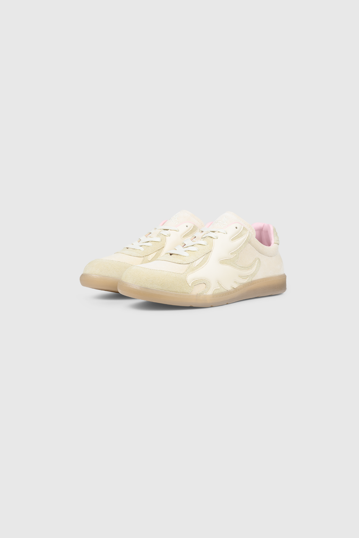 Cream-colored handmade leather Army Trainer sneakers by PESOCLO, featuring beige gum soles and a prominent stylized bird design on the side. The light pink interior lining and embroidered logo on the tongue provide distinctive finishing touches. The shoes are displayed against a plain light gray background.