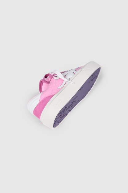 The PESOCLO Peso Skate sneaker is shown on its side, featuring a pink and white canvas-suede upper with white laces and revealing a purple Sole Artwork. The shoe is displayed against a plain, light gray background.