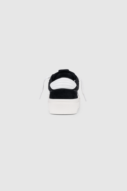 Back view of the PESOCLO Peso Skate sneaker in black, showcasing an artwork upper crafted from a canvas-suede mix, white laces, and a thick white sole, all centered on a plain light gray background.