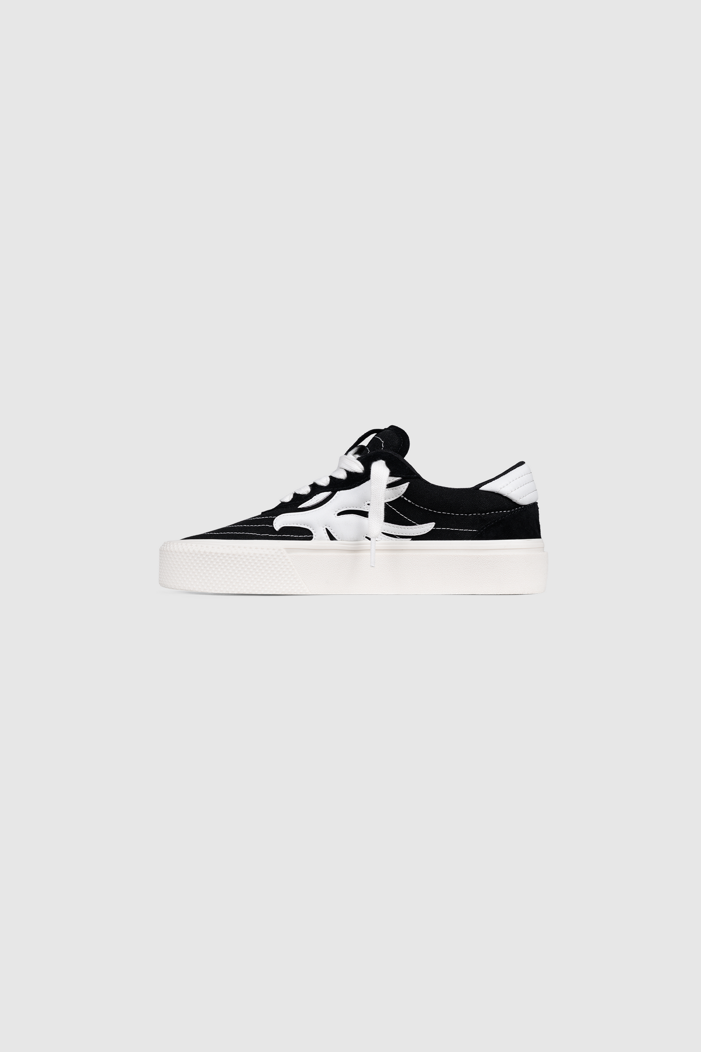 The Peso Skate by PESOCLO is a black and white low-top sneaker featuring a canvas-suede mix artwork upper, white laces, a signature white side stripe, and a thick white sole, shown against a plain gray background.