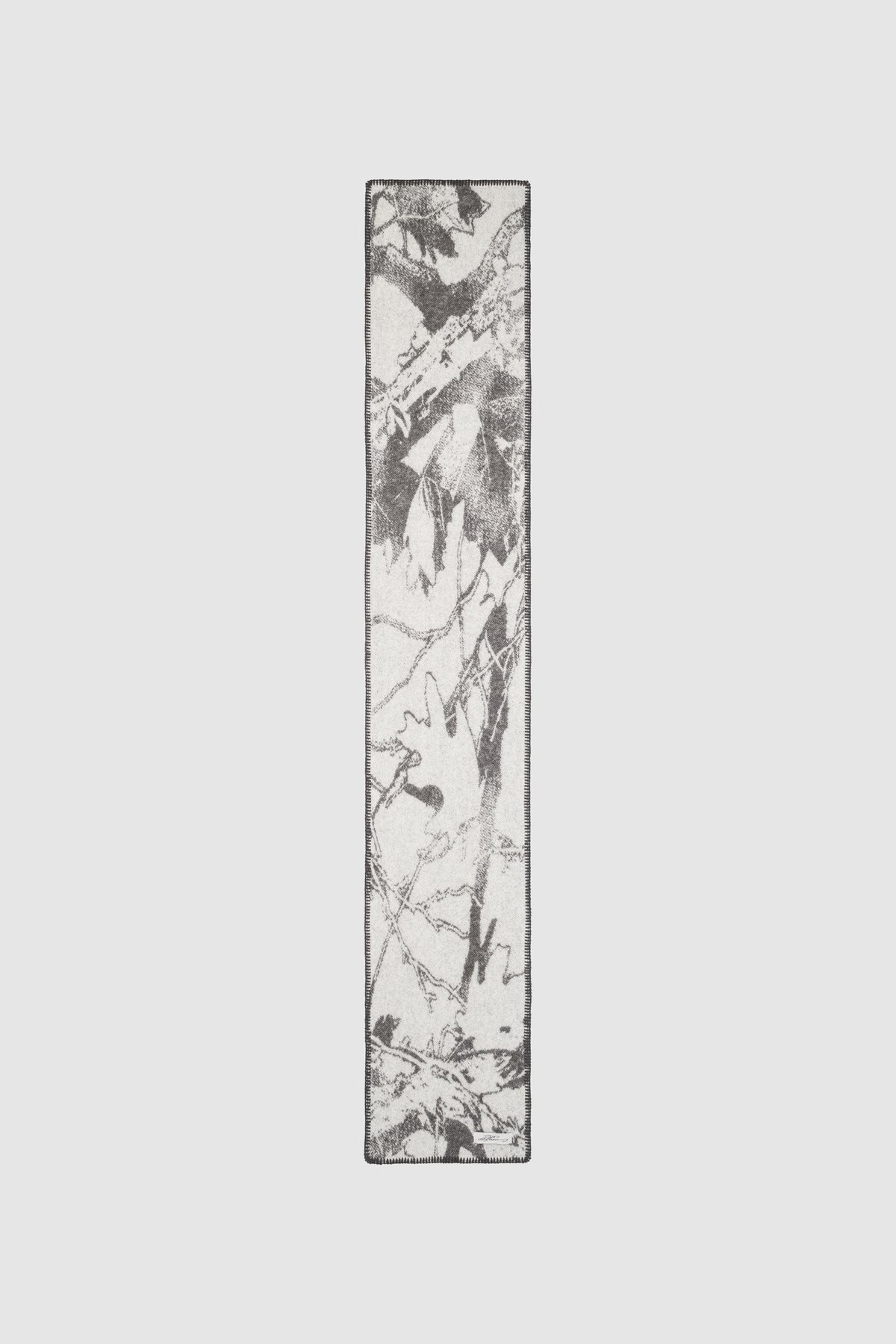A rectangular Hunter Scarf by PESOCLO, available in one size, featuring a black and white abstract leaf pattern on a light background reminiscent of a modern camo print, displayed against a plain white surface. Crafted from 100% Wolle for lasting comfort and style.